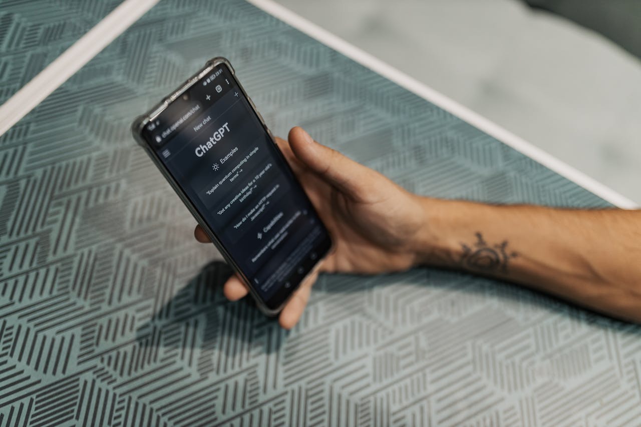 a hand holds a cell phone with Chat GPT loaded on the screen